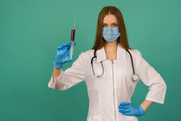 Covid19,冠状病毒。肖像专业自信的年轻白种人医生在医疗口罩和白大褂，听诊器在颈部，与疫苗注射器在手里，与疾病图片下载