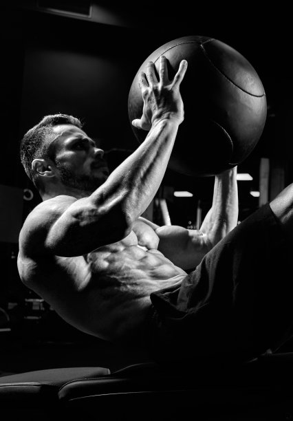 在长凳上训练腹肌的男人的单色肖像。图片下载