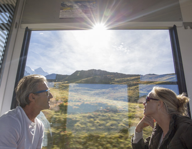 一对成熟的夫妇在行驶的火车上欣赏路过的风景图片下载