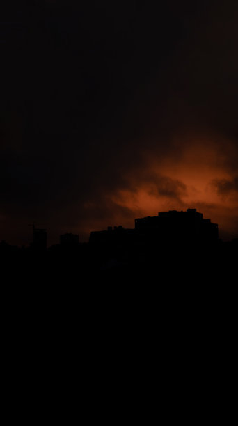 摘要建筑剪影黑暗的城市地标视图在暴风雨的日落戏剧性的橙色和黑色的天空背景垂直图片格式图片下载
