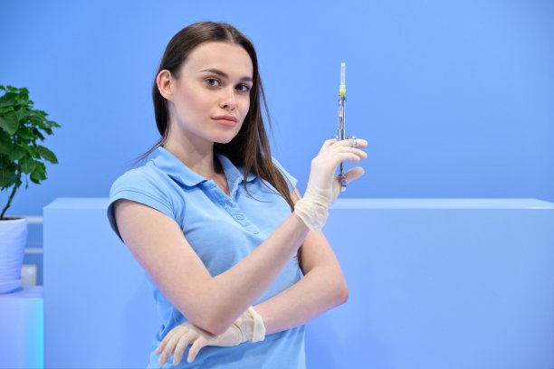 年轻漂亮的女护士拿着注射器，穿制服的女医生看着镜头图片下载