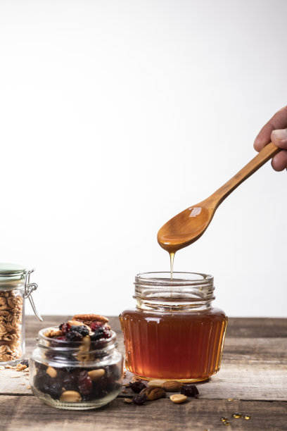蜂蜜滴进玻璃瓶。图片下载