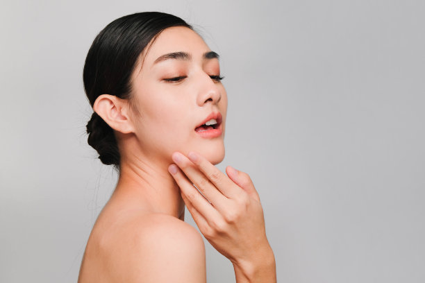 年轻美丽的亚洲女性，干净，新鲜和明亮的皮肤，快乐和开朗与积极的情绪，隔离在灰色背景，美容化妆品和面部治疗概念图片下载