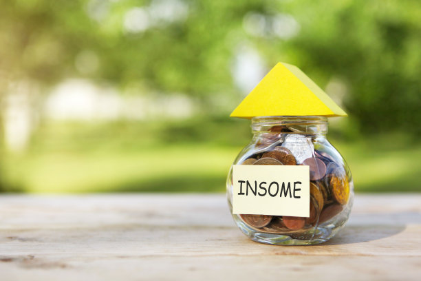 收入。玻璃罐与硬币和一个黄色的三角形从上面，在一个木桌上，自然的背景。高质量的照片图片下载