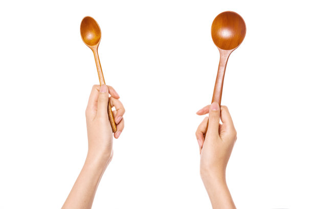 女人两手拿着木勺孤立在白色上。图片下载
