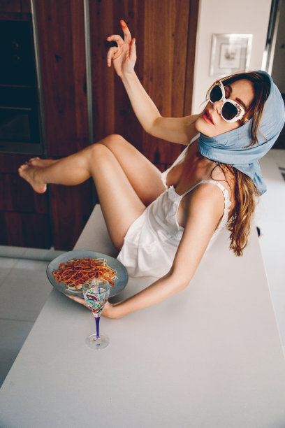 性感时尚女人摆姿势和吃意大利面图片下载