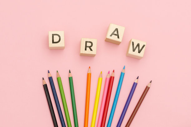 多色铅笔在粉红色的背景上刻有题词的立方体上画。图片下载