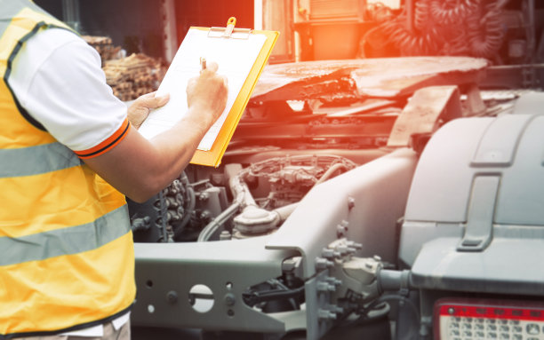 一个卡车司机拿着剪贴板检查半挂车的安全。图片下载