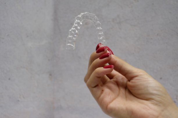 在灰色背景的女人的手握牙齿对准的特写图片下载