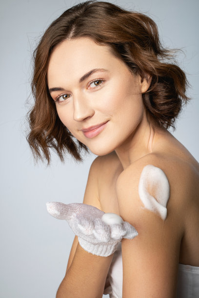 迷人的年轻女子使用身体清洁泡沫图片下载