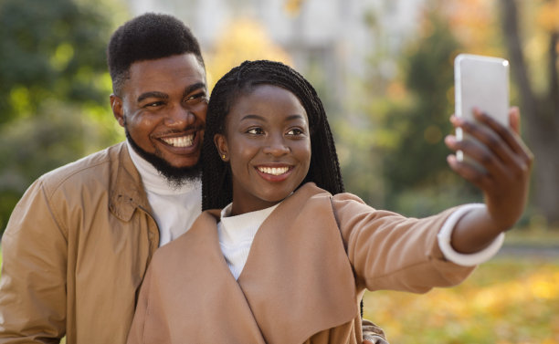 浪漫的非裔美国情侣在户外用智能手机自拍图片下载