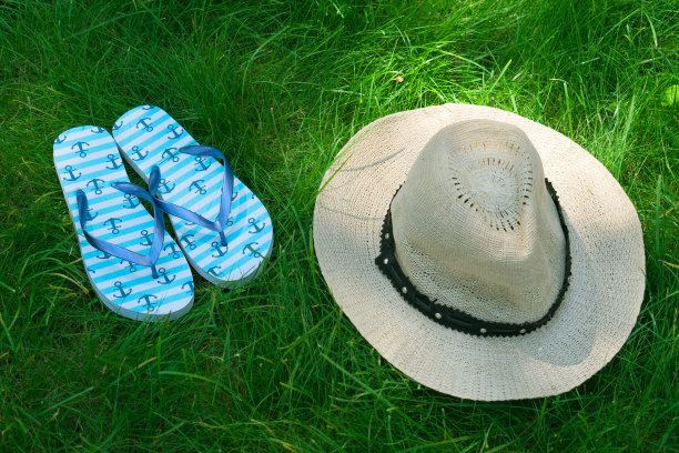 蓝色人字拖和太阳帽在绿色草地上。前视图。图片下载