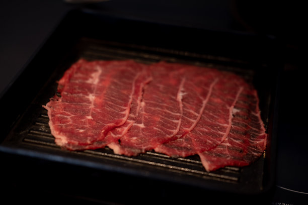 新鲜的生猪肉牛肉片烤在黑色托盘。切成薄片的猪肉。图片下载