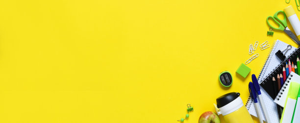回到学校。黄色背景上的学校用品和一个苹果。布置学校用品。远程学习。图片下载