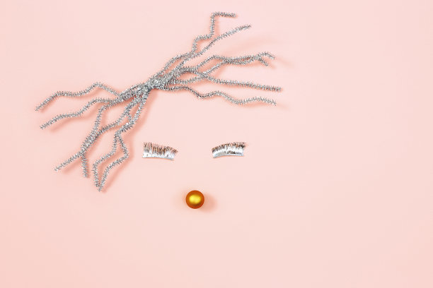 抽象的脸，圣诞节日的概念。极简主义的女人肖像从银箔装饰上粉粉背景。图片下载