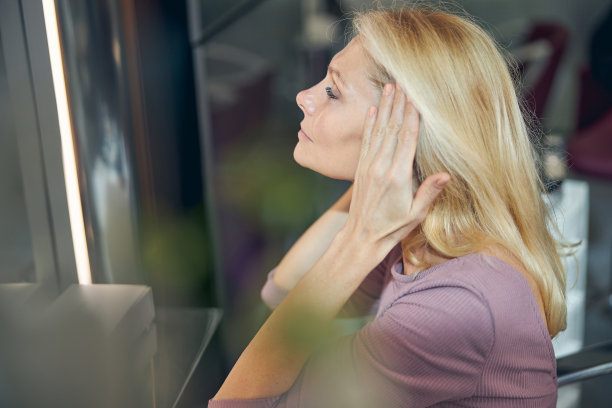 一个漂亮的金发美女看着她的倒影的资料照片图片下载