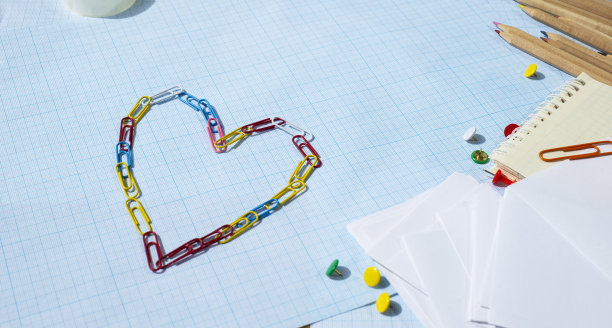 文具架上的蓝色坐标纸。颜料、铅笔、记事本、纸和别针制成的心。最喜欢的商务。最喜欢的爱好。为文本复制空间。图片下载