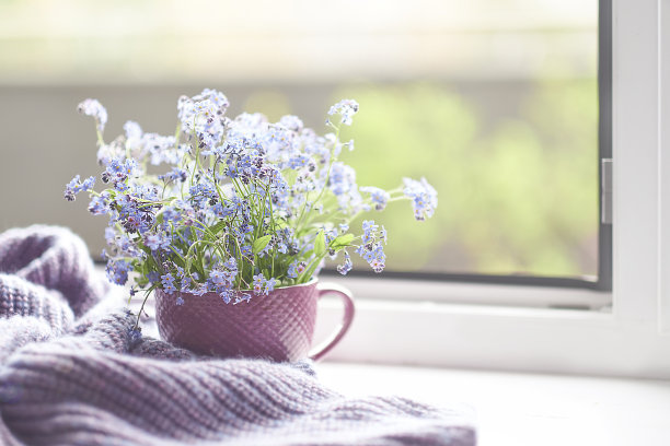 紫色温暖的格子毯子放在木制的乡村长椅上。照片色调，选择性聚焦。温馨的家居静物:窗台上盛开着温暖格子图案的春花图片下载