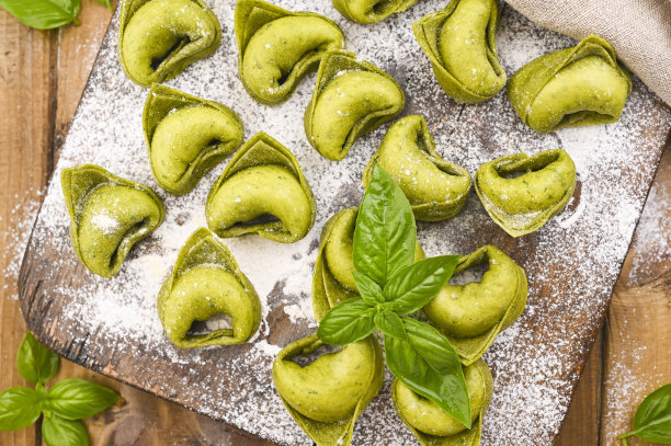 意式饺子意大利的典型菜肴。食物背景自制生意大利饺子和绿色香蒜沙司的原料在木制的背景。高角度的观点。副本的空间。图片下载