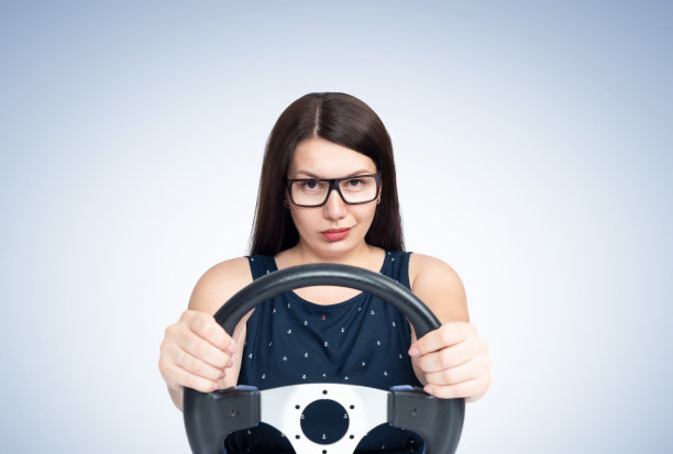 性感年轻微笑快乐的女孩与眼镜驾驶汽车，前视图图片下载