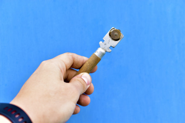 特殊刀片在玻璃上，在蓝色背景上。蓝色背景上的特制玻璃切割器图片下载