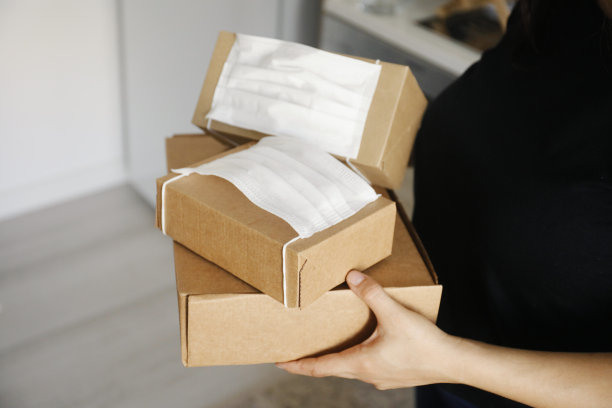 女性双手捧着盒子，戴着口罩图片下载