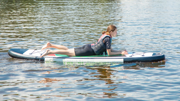 一个运动女孩的照片在一个十几岁的服装休息在一个SUP板在水后一个积极的锻炼。对青少年体育。夏季。积极健康的生活方式。营图片下载