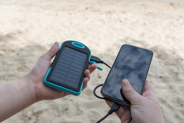 女性一手拿着太阳能电池，一手拿着黑色智能手机。图片下载