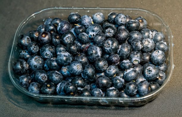 深色背景上的塑料包装盒装蓝莓图片下载