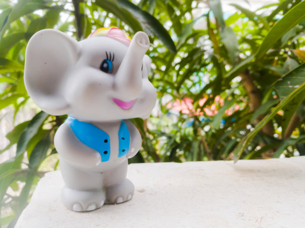 一只玩具象穿着蓝色的外套，戴着一顶长鼻子和微笑的帽子。图片下载