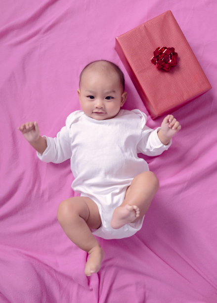 可爱的亚洲婴儿微笑着睡觉旁边的礼盒。专注于脸图片下载