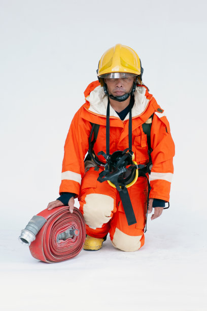 一幅身穿红色防护服、面罩和头盔的亚洲男性消防员的肖像，灭火器坐在白色背景上。图片下载