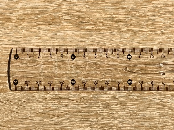 木桌上的透明塑料校尺。毫米和厘米用黑色标记。用尺子量长度和宽度图片下载