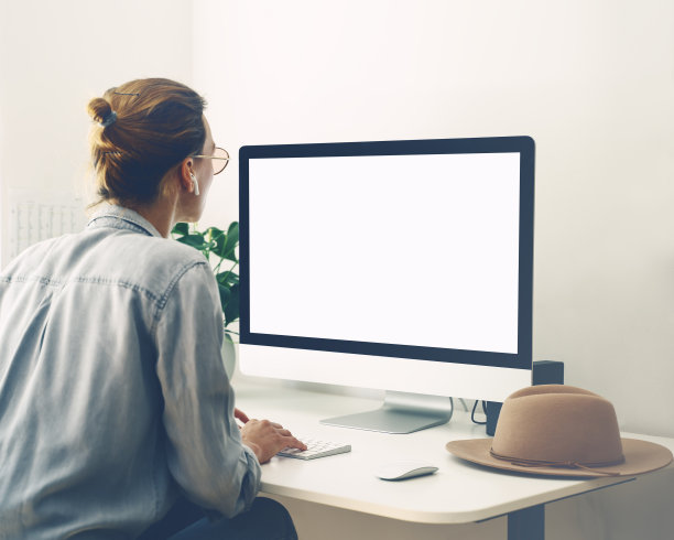 在家庭办公室使用电脑工作的女性。工作场所，创意工作者的办公桌。图片下载