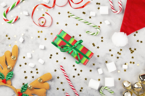 圣诞组成。礼物，焦糖手杖，棉花糖，圣诞老人帽，头带鹿角在灰色的混凝土背景和闪闪发光的星星。寒假的概念。俯视图图片下载