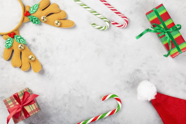 圣诞组成。礼物，焦糖手杖，圣诞老人帽，灰色混凝土背景上的头带鹿角。寒假的概念。前视图。本空间图片下载