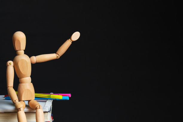 木制的娃娃坐在书和办公用品点复制空间图片下载