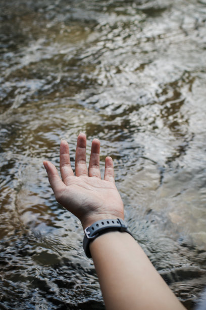 在阳光明媚、温暖的户外，手在河流中流动的水里触摸，图片下载