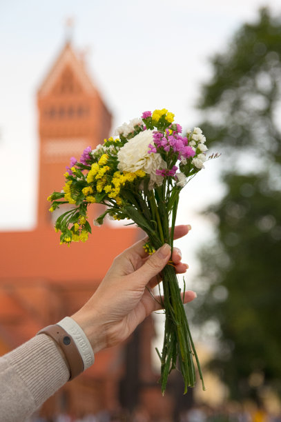 在一座红色教堂的背景上，手持一束野花图片下载