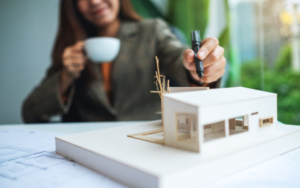 一位女建筑师正在用图纸制作建筑房屋模型图片下载