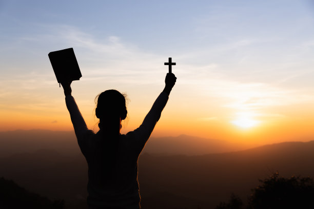 在明亮的阳光下，手持十字架的双手向上帝祈祷。图片下载