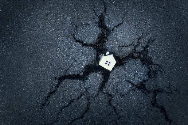 住宅概念的破坏与小玩具房子在一个裂缝的沥青洞。图片下载