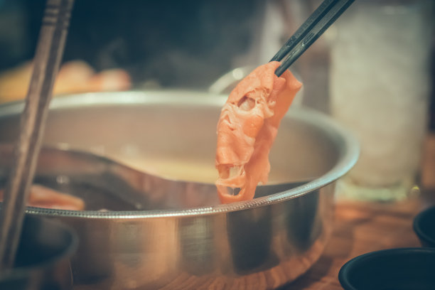 手握猪肉用筷子在火锅与烟日式火锅图片下载