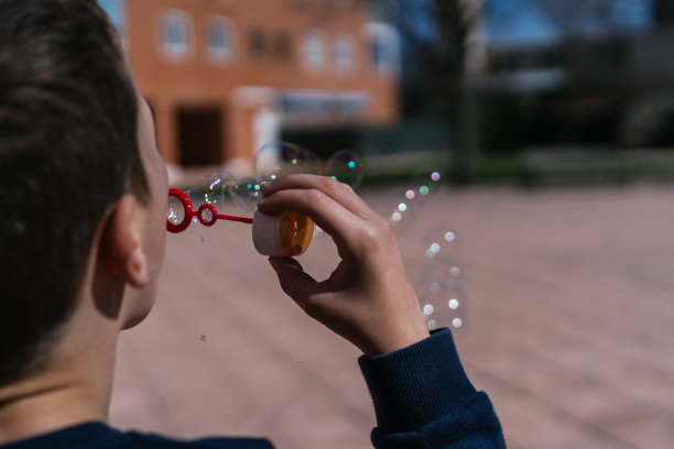 照片拍的是一个穿着蓝色衣服的男孩一边吹着泡泡图片下载