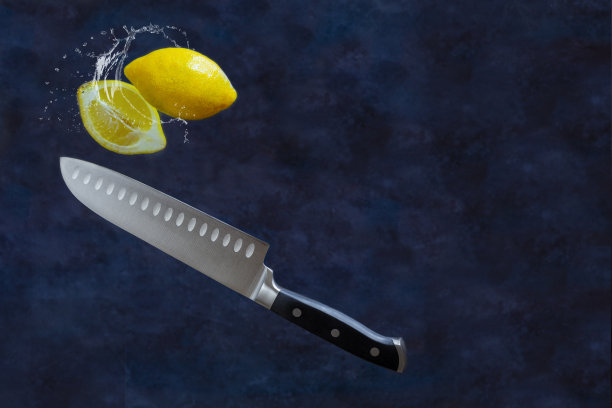 柠檬水溅成两半，用水果刀在深色背景上切开。食物悬浮图片下载