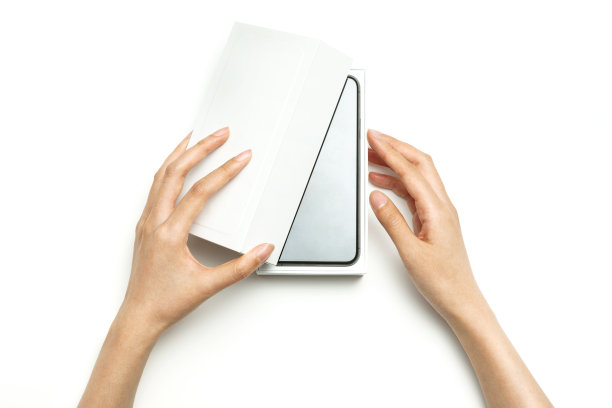 女人手里拿着一个白色的包装箱孤立在白色的箱子上。图片下载