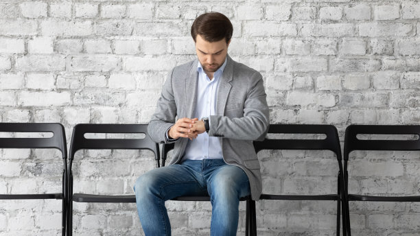 22、自信的男人应试者一边看时间，一边看手表图片下载