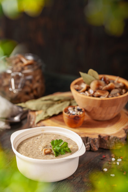 自制的蜂蜜木耳奶油汤在木碗和打开的玻璃罐中，香料，勺子，餐巾，在木桌上。腌制蘑菇。发酵的健康食品。图片下载