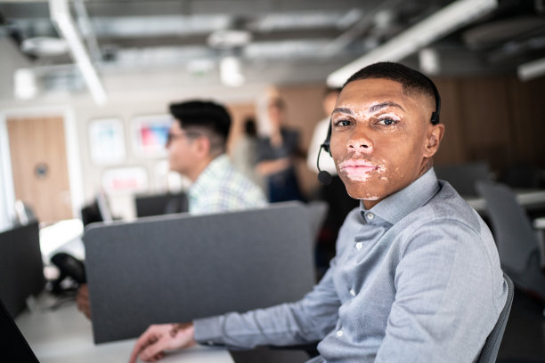 在办公室呼叫中心使用耳机工作的员工肖像图片下载