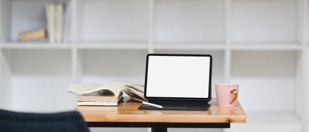 一张木桌上放着一个带键盘壳的白色空白屏幕的电脑平板电脑。图片下载